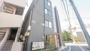 A modern building with a grey facade, a visible entrance, and a small garden area. - Gran FusionIkebukuro (Tokyo)