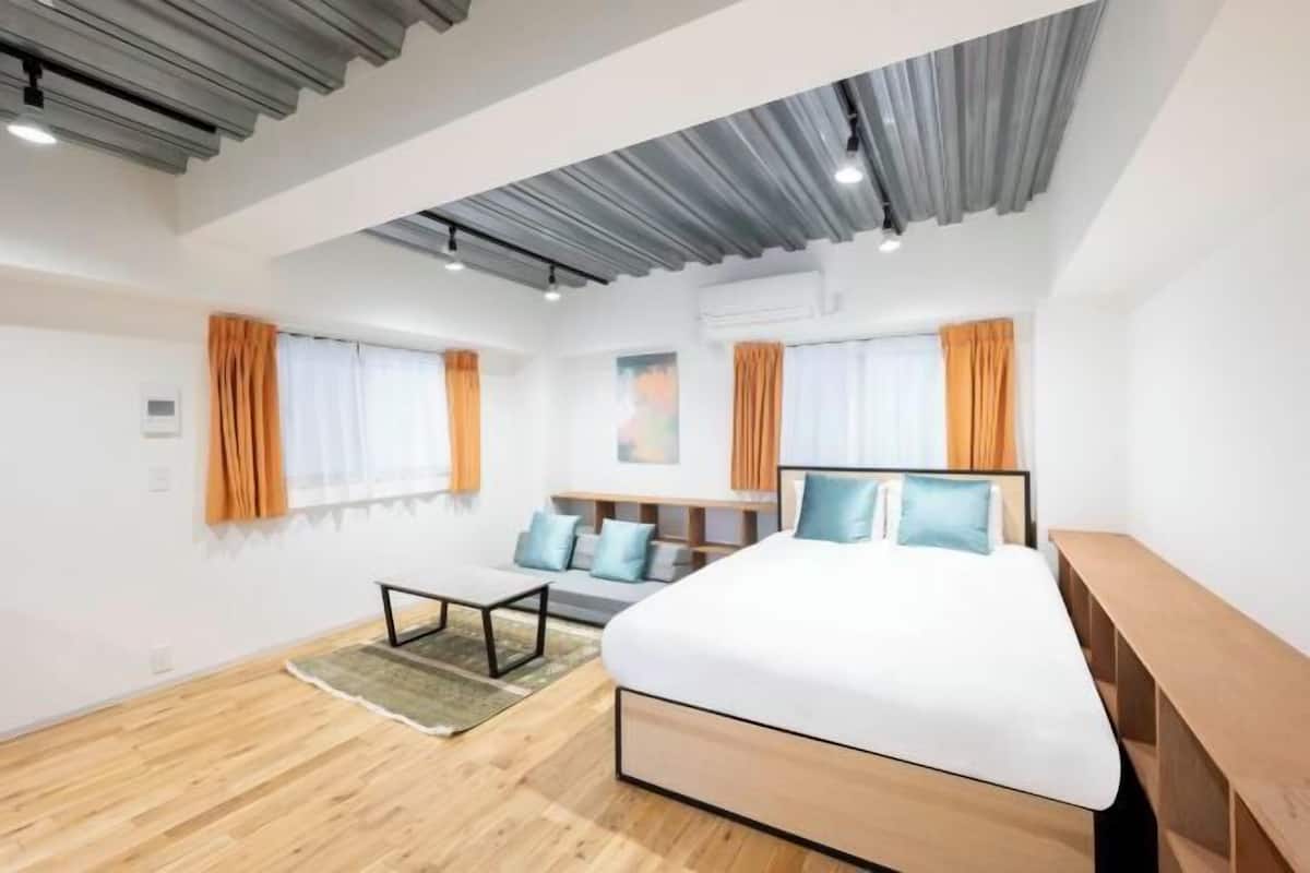 A modern hotel room with a large bed, a desk, and a sofa.