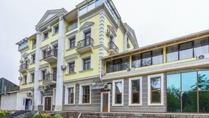 A multi-story building with balconies, large windows, and a stone base. - Aykun Hotel (Almaty)