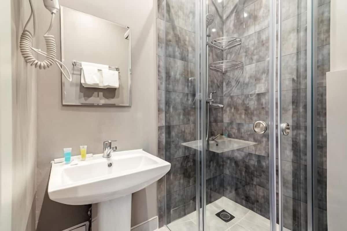 A modern bathroom with a glass-enclosed shower, a white sink, and a mirror.