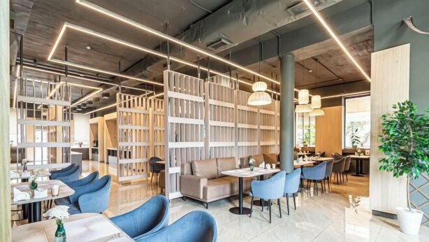 A modern interior with a bar area, seating, and a large bookshelf. - Aykun Hotel (Almaty)