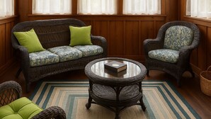 A cozy room with a wooden paneled wall, a sofa with green cushions, a patterned armchair, and a round table with a book. - Cozy Ranch Retreat Near Jefferson City - Fun Games, Activities, Sports, & Land! (Loose Creek)
