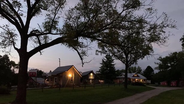 A rural setting with a dirt path leading to a row of wooden buildings, possibly a farm or guesthouse. - Cozy Ranch Retreat Near Jefferson City - Fun Games, Activities, Sports, & Land! (Loose Creek)