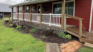 A red house with a wooden porch and a brick pathway leading to the front door. - Cozy Ranch Retreat Near Jefferson City - Fun Games, Activities, Sports, & Land! (Loose Creek)