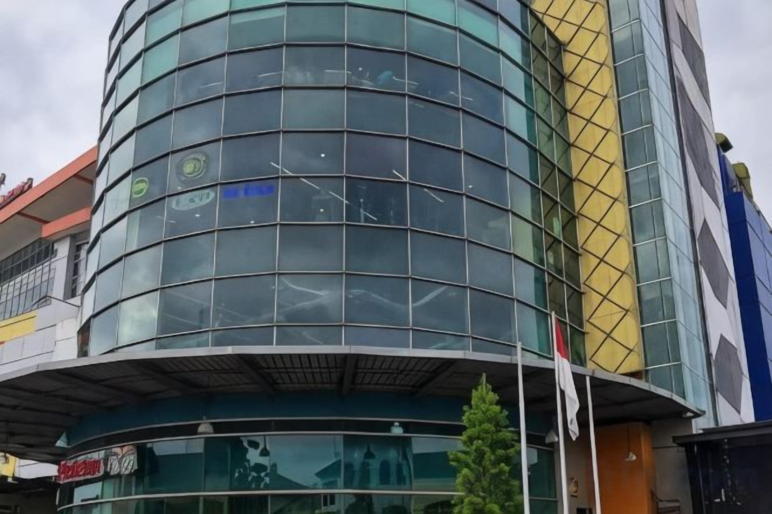 Un edificio moderno con fachada de vidrio curvada y una entrada visible.