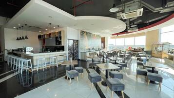Ein modernes Restaurant mit Barbereich, Sitzgelegenheiten und Blick auf die Stadt.