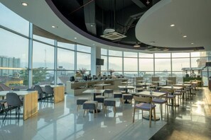 A spacious, modern dining area with high ceilings and large windows offering views of the cityscape.