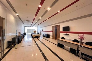 A hotel lobby with a reception desk, seating area, and a television screen. - Hotel Metro Indah Bandung (Bandung City)