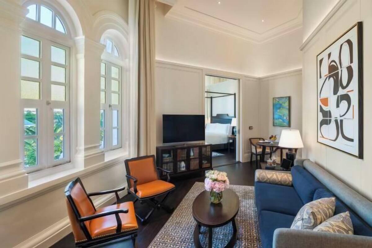 A spacious living room with a sofa, armchairs, a coffee table, and a TV.