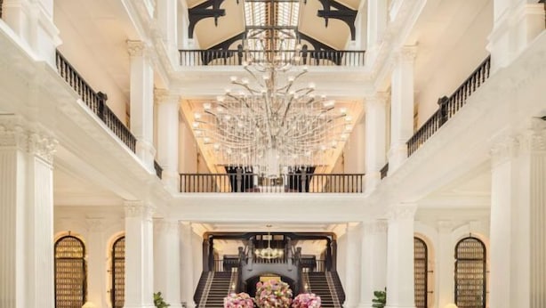 A grand interior with a central staircase, ornate columns, and a chandelier. - Raffles Singapore (Singapore)