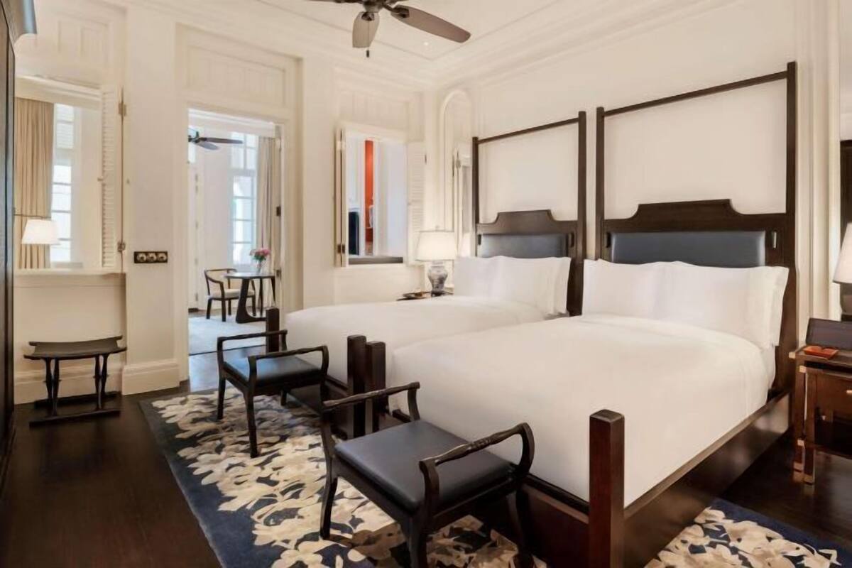 A hotel room with two beds, a desk, and a chair.