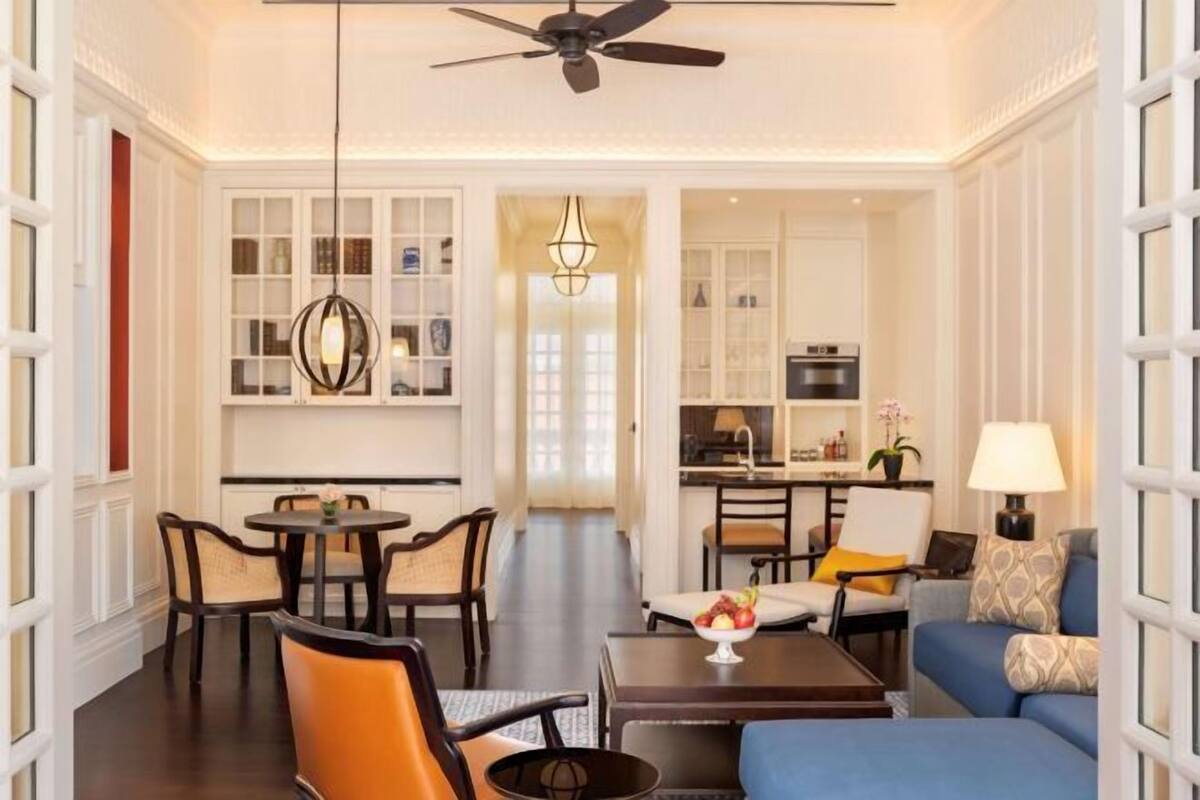 A spacious living area with a dining table, chairs, a sofa, and a kitchen in the background.