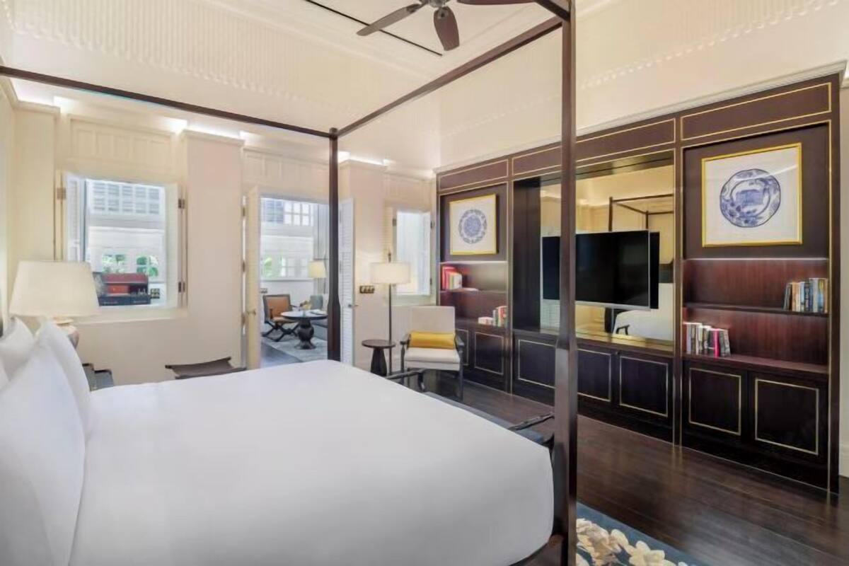 A hotel room with a large bed, a television, a bookshelf, and a desk.