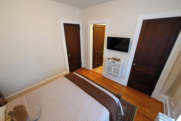 A bedroom with a bed, a TV, and two doors.