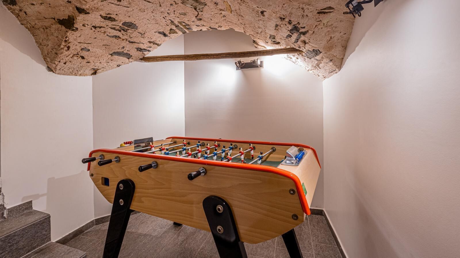 Una mesa de fútbol de mesa en una habitación con paredes blancas y techo con textura.