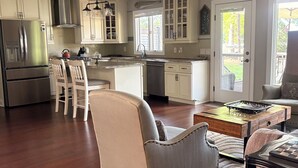A spacious kitchen with modern appliances, a dining area with a chair, and a view through a door.