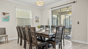 A dining area with a wooden table set for six, surrounded by dark wooden chairs. - 6BR Disney Retreat w/ Pool, Game Loft & Resort Amenities (Kissimmee)