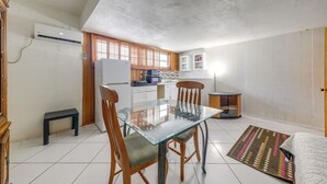 A compact kitchen with a glass dining table, wooden chairs, a small bench, and a refrigerator. - Canal-front Stay w/ Shared Pool, Near Hard Rock! (Miramar)