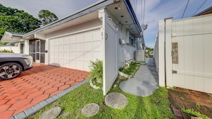 A modern house with a garage, a paved driveway, and a small garden area with stepping stones. - Canal-front Stay w/ Shared Pool, Near Hard Rock! (Miramar)