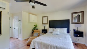 A bedroom with a large bed, a ceiling fan, a nightstand, a lamp, a mirror, and a door leading to another room. - Close to Hospitals: Peaceful Birmingham Studio (Birmingham)