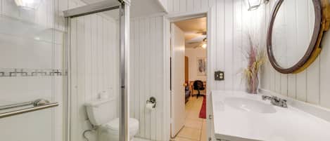 A bathroom with a glass-enclosed shower, a white sink, and a wooden-framed mirror.