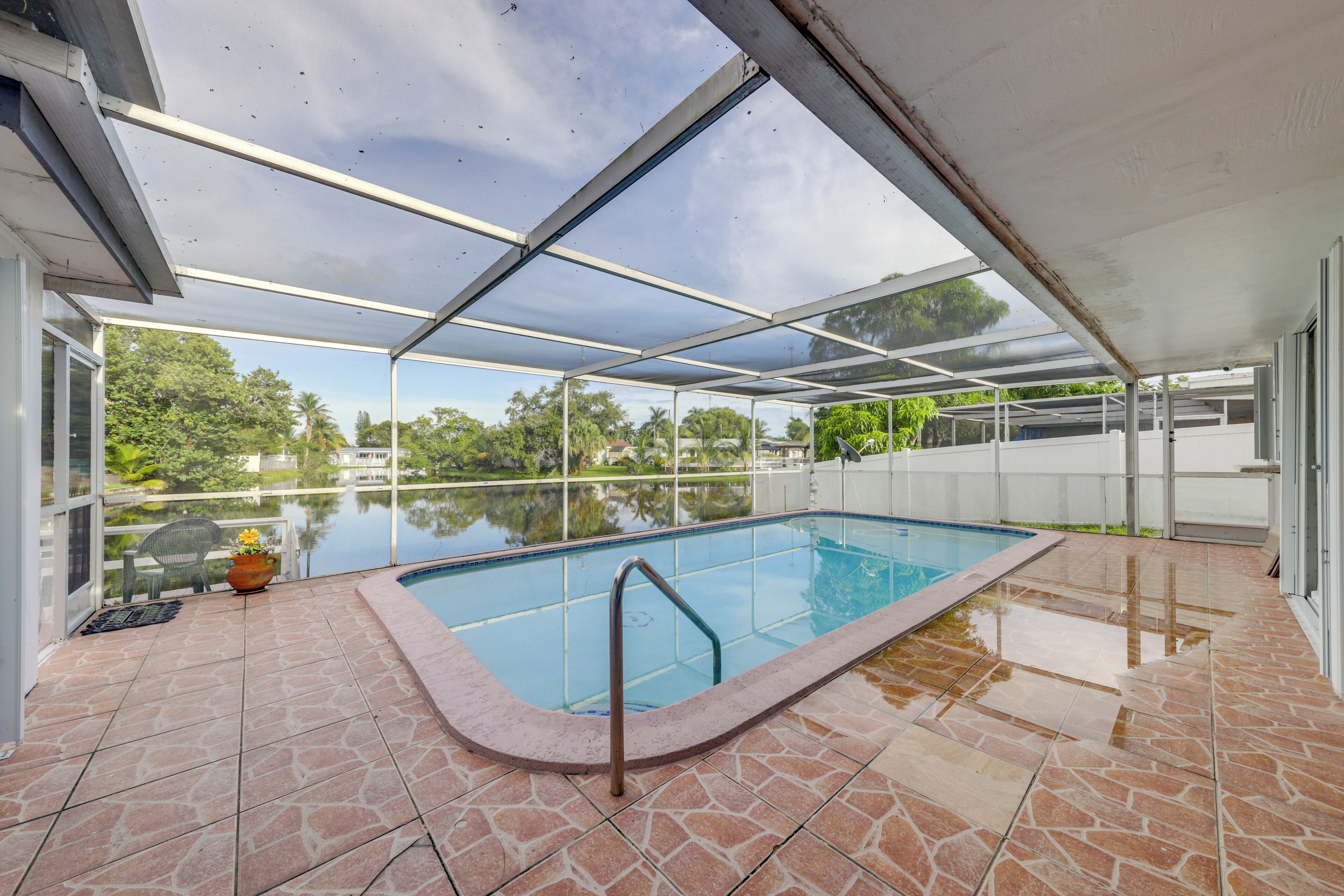 A covered swimming pool with a stone-tiled deck and a glass ceiling.