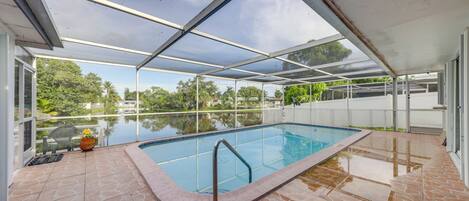 A covered swimming pool with a stone-tiled deck and a glass ceiling.