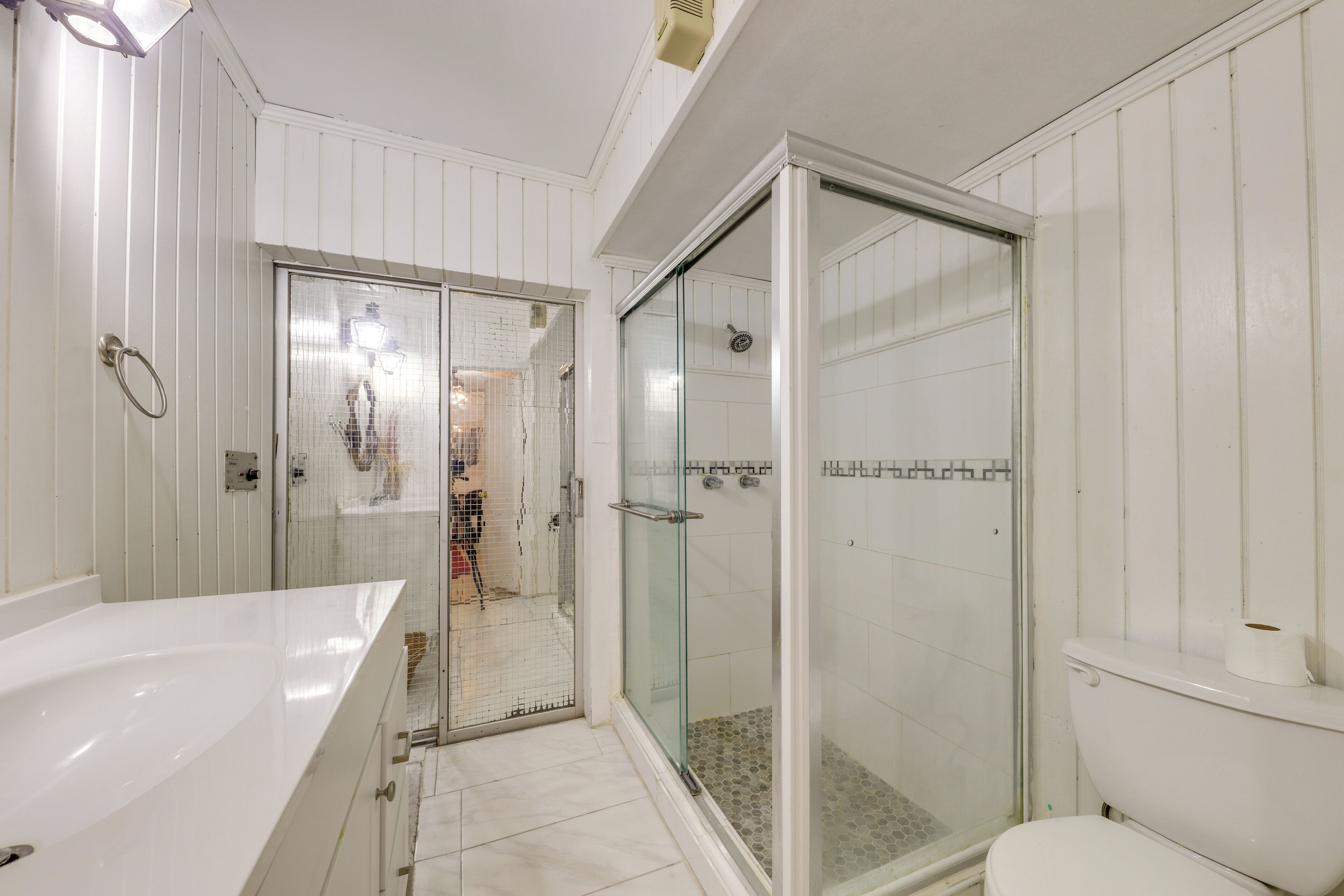 A bathroom with a glass-enclosed shower, a white sink, and a toilet.