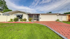 Une maison de plain-pied avec un garage, une allée pavée et une pelouse bien entretenue.
