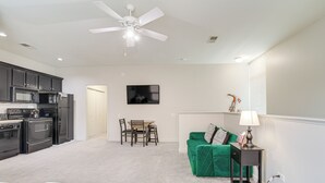 A compact living space with a kitchenette, a dining area, and a green sofa.