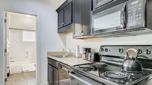 A modern kitchen with stainless steel appliances, including a stove, microwave, and coffee maker.