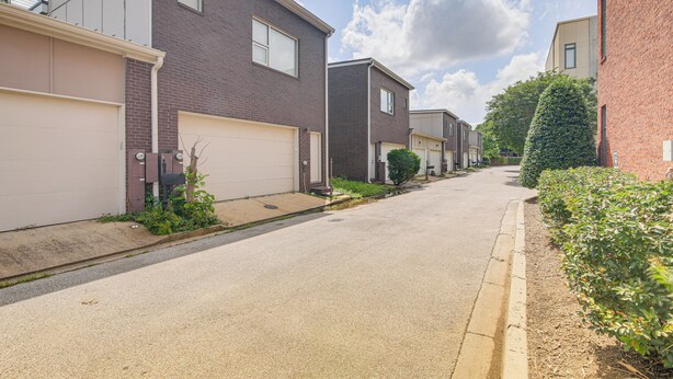 A residential street with houses, a clear sky, and a sidewalk.