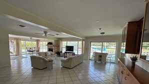 Un salon spacieux avec une cheminée, un téléviseur et un coin repas offrant une vue sur une piscine.