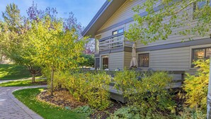 A modern house with a paved driveway, a well-maintained garden, and a patio area with outdoor furniture.