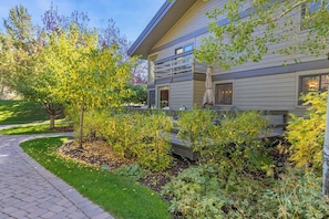 A modern house with a paved driveway, a well-maintained garden, and a patio area with outdoor furniture.