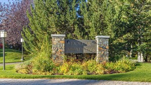A sign for Dollar Meadows with stone pillars and a landscaped garden.