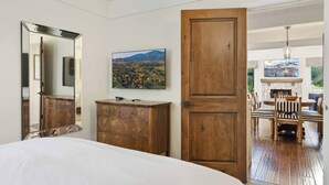 A bedroom with a large bed, wooden dresser, and a painting on the wall.