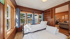 A wooden cabin with two beds, a sofa, and a dining area.