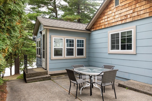 Private patio w/ outdoor dining set, perfect for relaxed al fresco meals surrounded by trees.