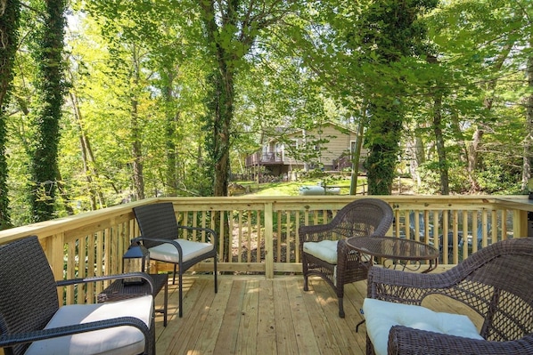 Une terrasse en bois, meublée de meubles en osier, avec vue sur un quartier résidentiel.