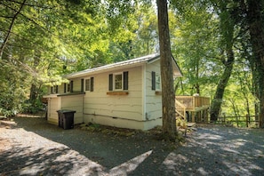Une cabane de plain-pied avec une terrasse, entourée d’arbres.