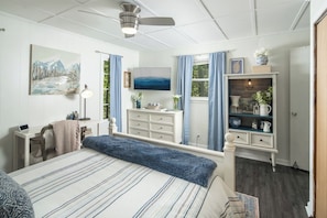 Une chambre à coucher comprenant un lit, un bureau, une commode, un téléviseur et une cheminée.