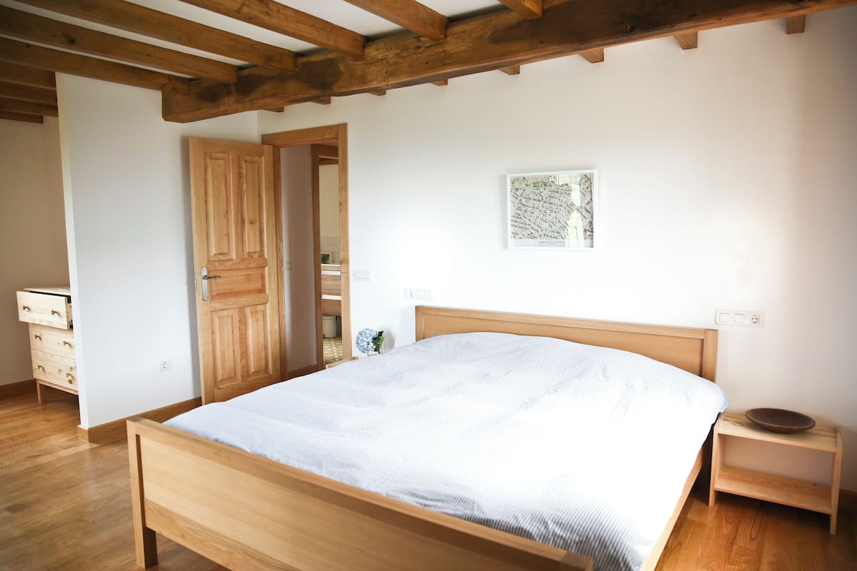 Una camera da letto con un letto, un comodino, una cassettiera e una porta, tutti in legno.