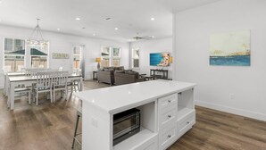 A spacious kitchen with a central island, dining area with white furniture, and a living room with a sofa and coffee table. - Ellis Sands with LSV, Arcade, and Billiards (Miramar Beach)