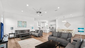 A modern living room with grey sofas, a black coffee table, and a TV on a stand. - Ellis Tide with LSV, Arcade, and Billiards (Miramar Beach)