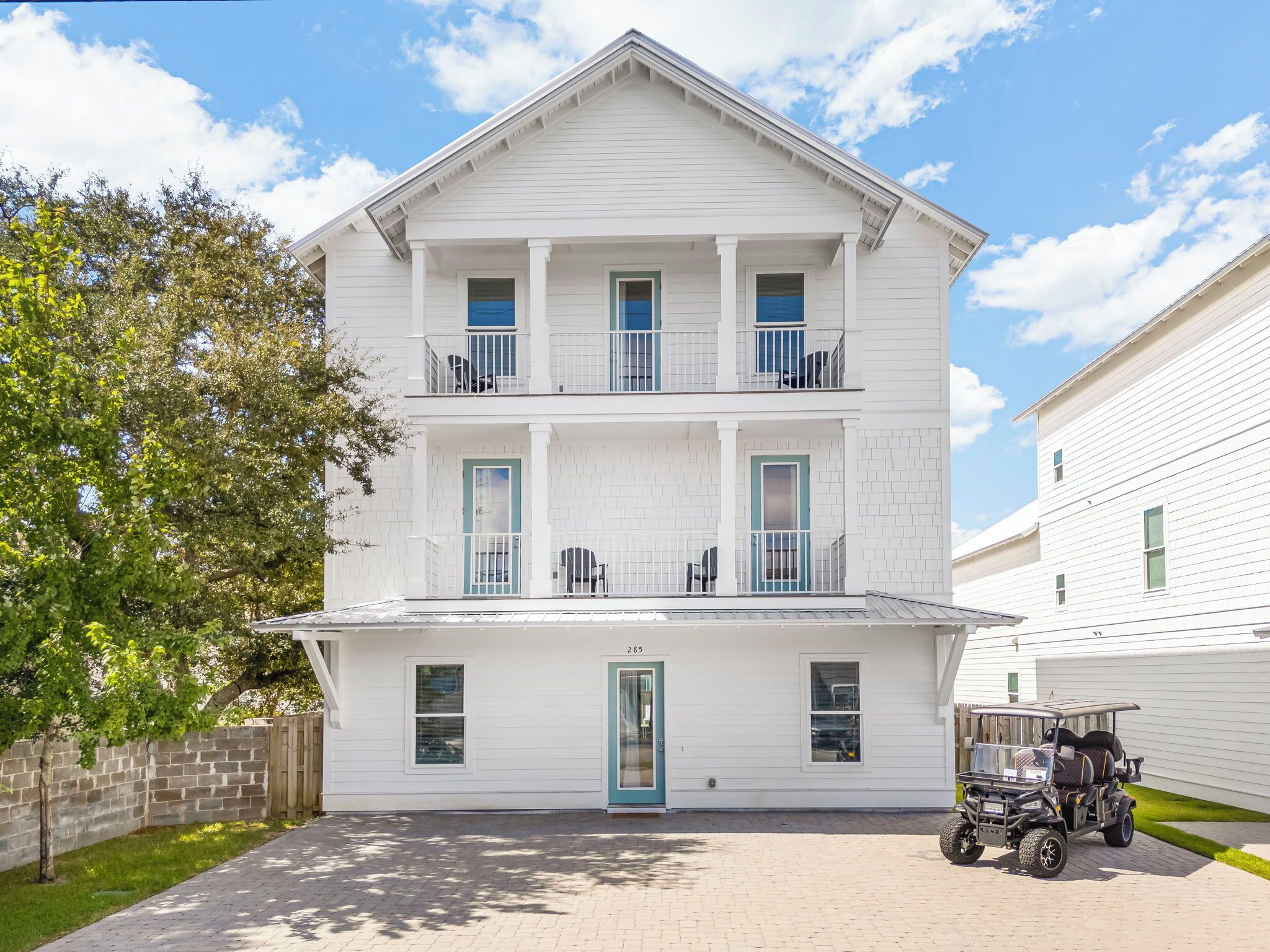 A two-story white house with a front porch, a garage, and a golf cart parked in front.
