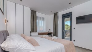 A modern bedroom with a bed, a desk, and a view of the outdoors. - Villa Taralis with heated pool (Kvarner - Kornić) (Kornić)