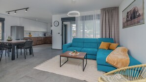 A modern living room with a teal sofa, a wooden coffee table, and a dining area with a table and chairs. - Villa Taralis with heated pool (Kvarner - Kornić) (Kornić)