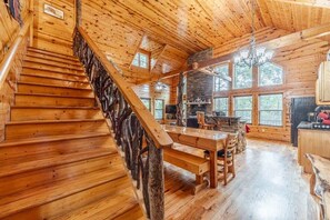 A wooden interior with a staircase, a dining area, and large windows. - FROHE HUTTE l PRIVATE LUXURY GETAWAY & GAME ROOM (Cleveland)