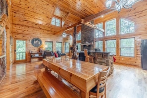A log cabin interior with a dining table, benches, a stone fireplace, and large windows. - FROHE HUTTE l PRIVATE LUXURY GETAWAY & GAME ROOM (Cleveland)